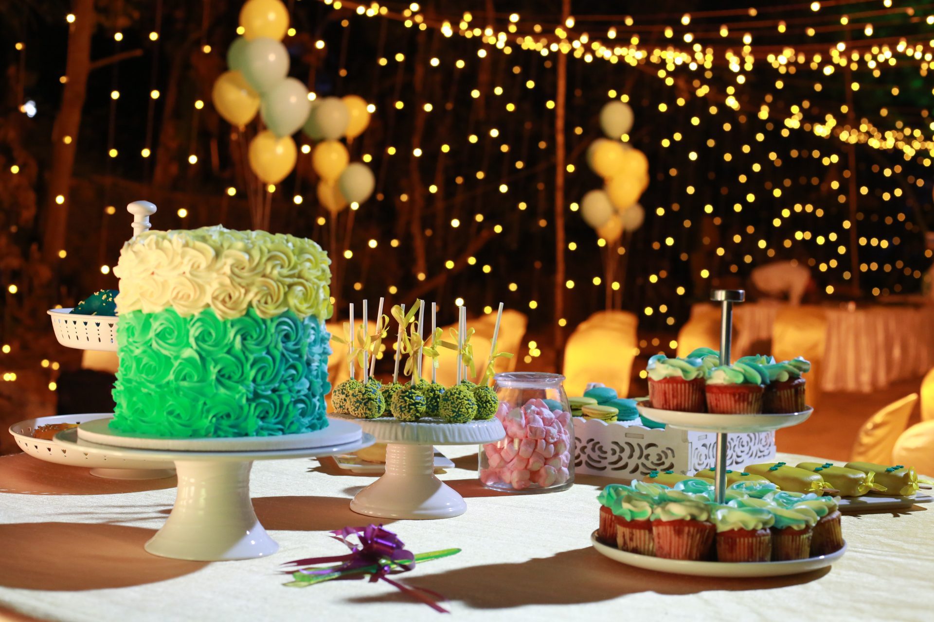 A decorative background with lights and cakes on the table